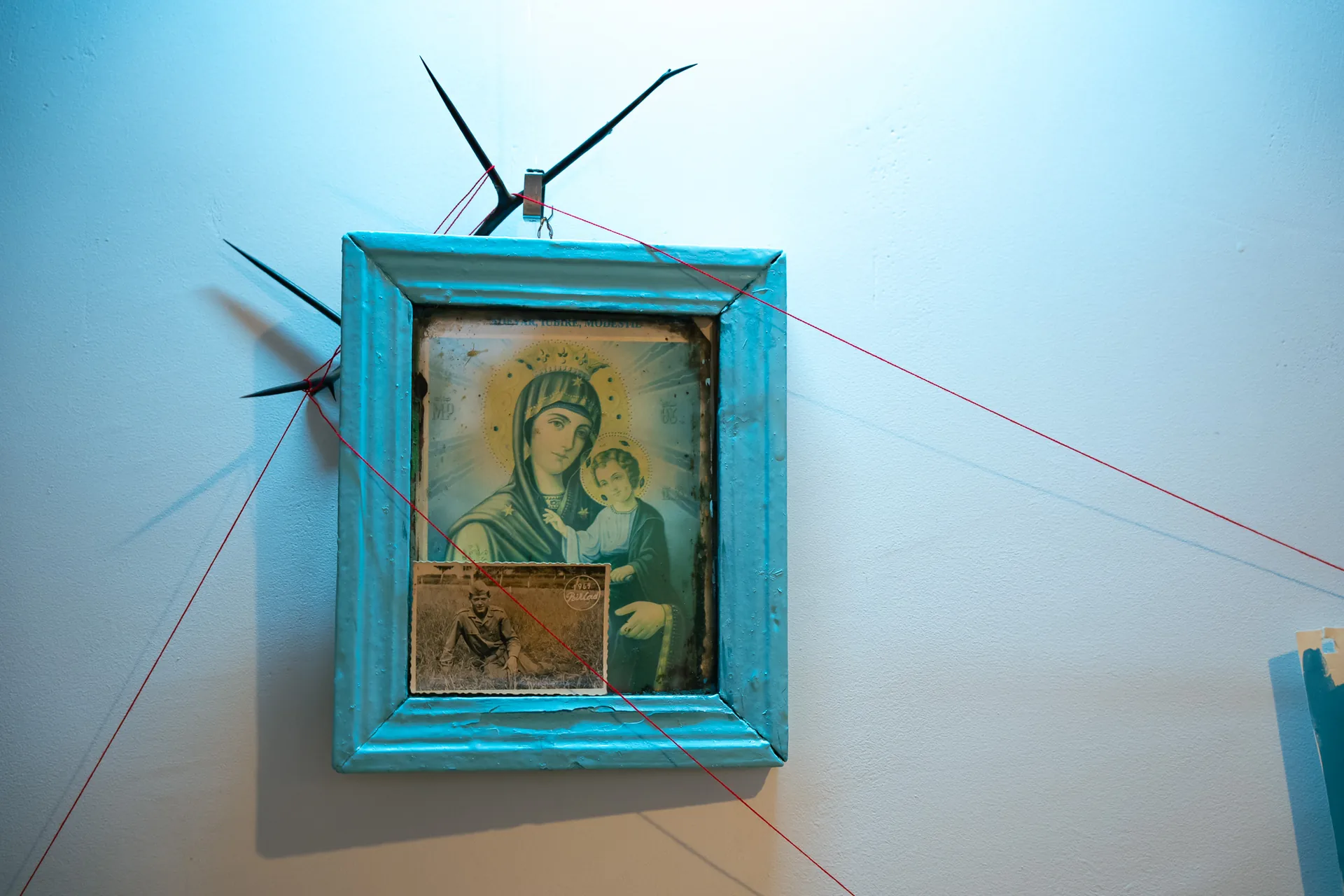 Horizontal close-up of the salvaged Orthodox icon at the apex of the installation with the grandfather's military photograph tucked into the frame