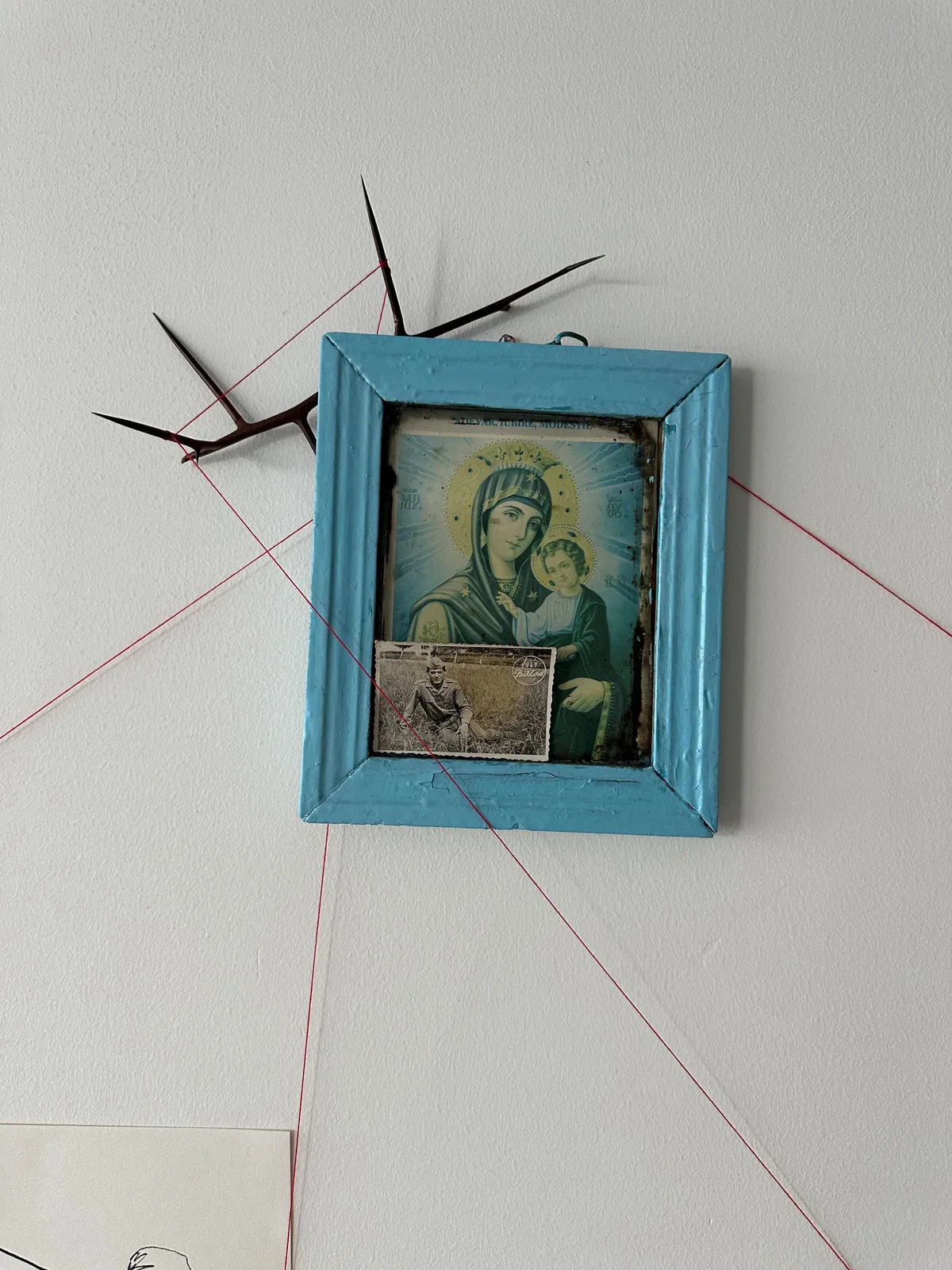 Close-up of the blue-framed Orthodox icon with grandfather's military portrait tucked inside