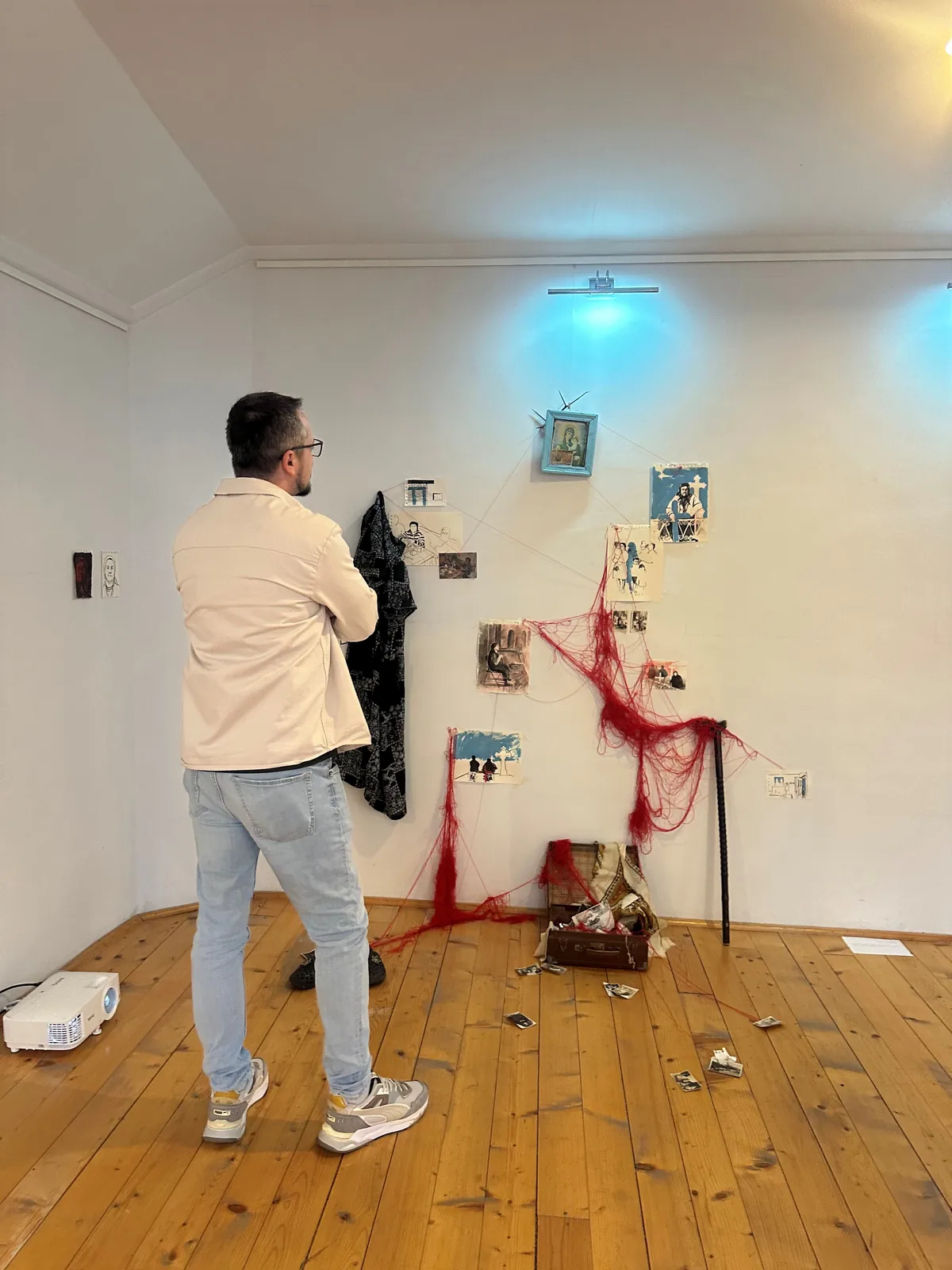 Low-angle view of the open vintage suitcase, walking stick, and scattered photographs on the floor