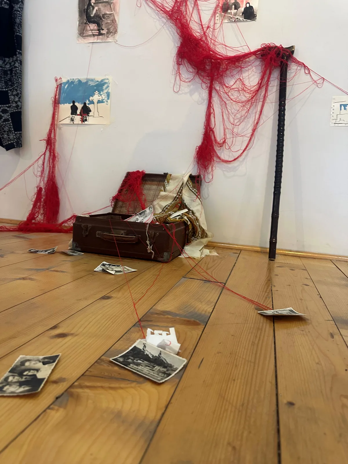 Red thread descending into the ancestral black-and-white patterned slippers on the wooden floor